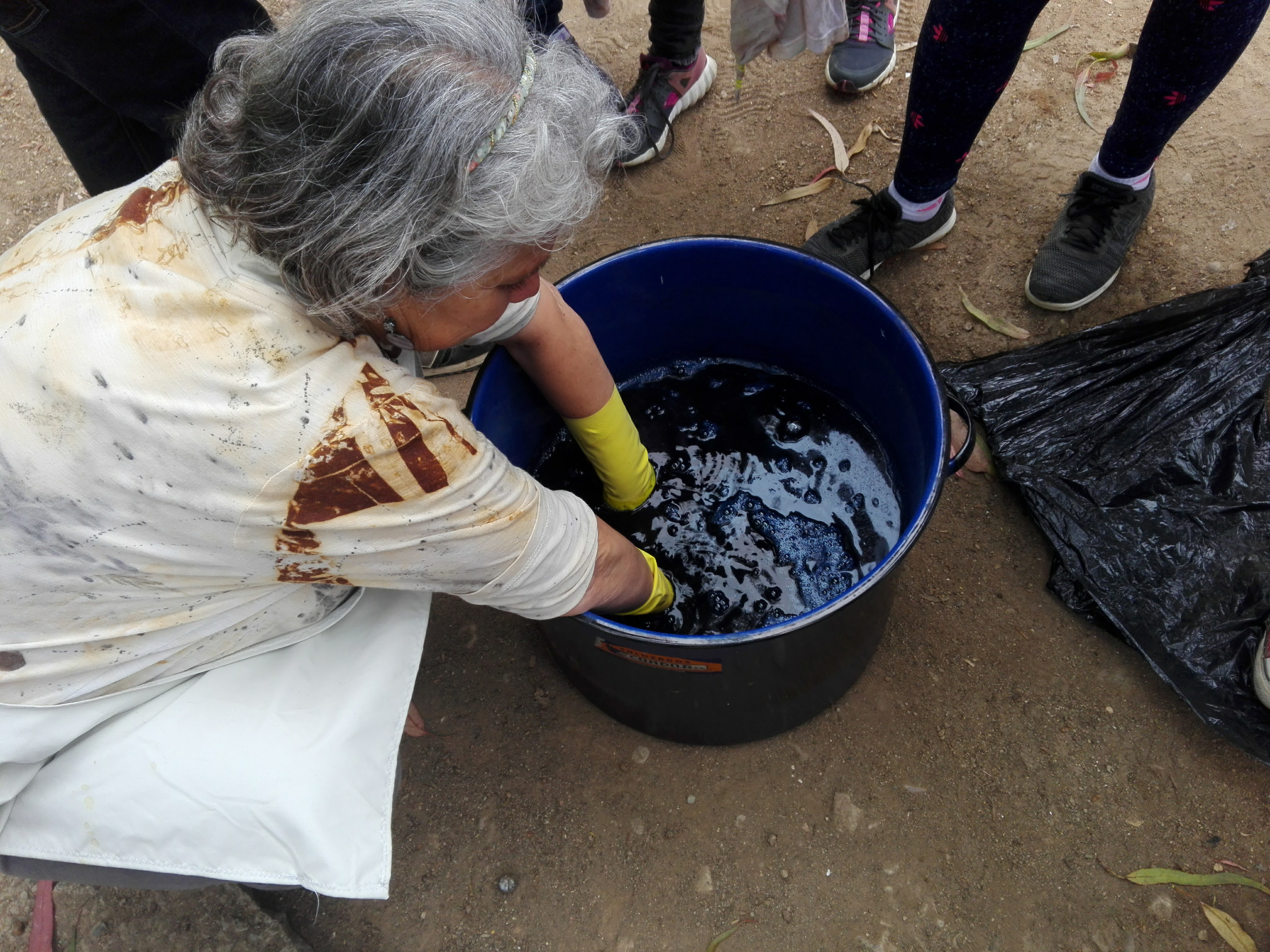 Susana Peñaloza sumergiendo textil en tina de tintura natural