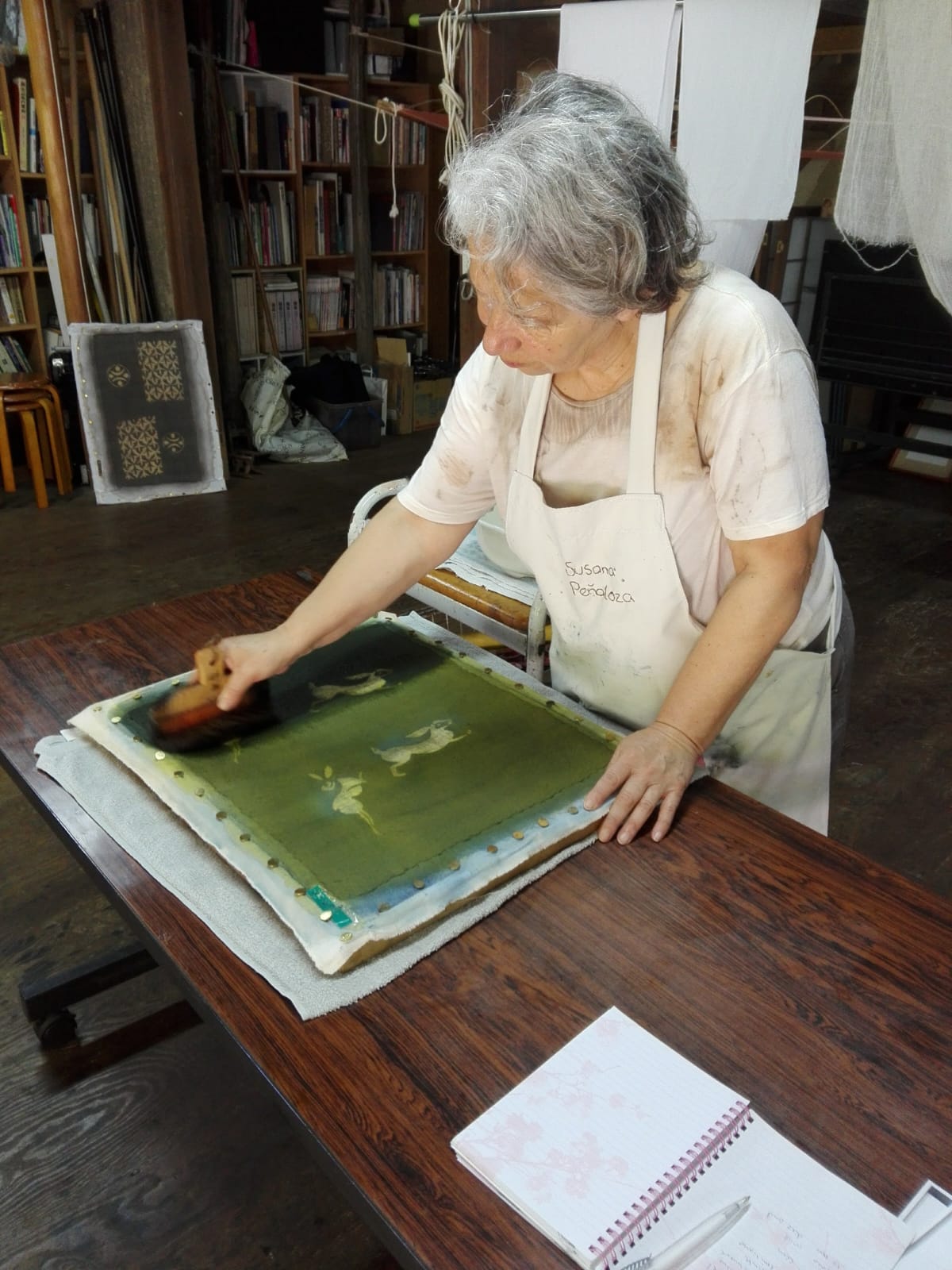 Susana Peñaloza aplicando color sobre una tela verde con conejos en katazome, Okazaki, Japón