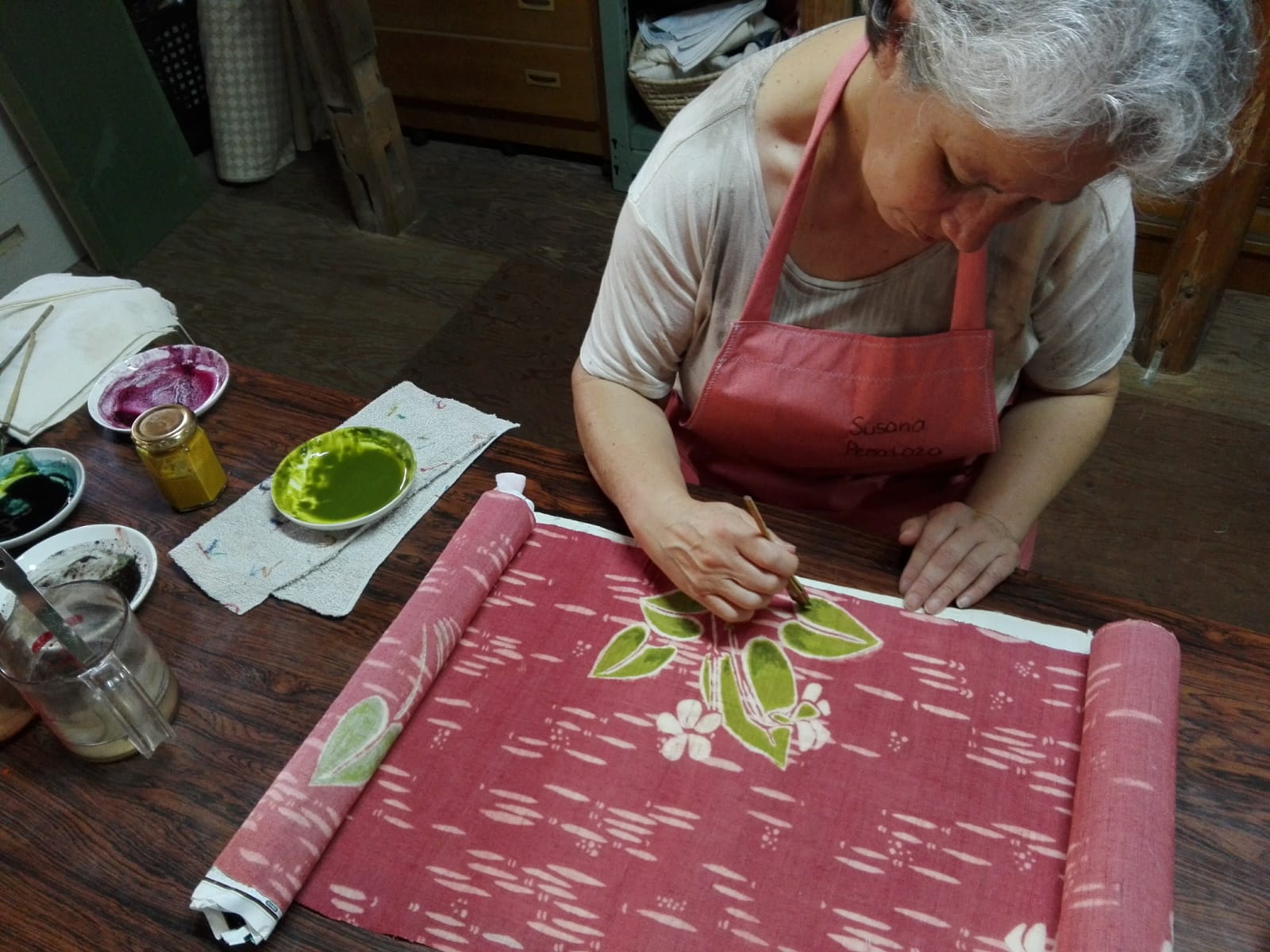 Susana Peñaloza pintando hojas verdes sobre una tela rosada en katazome, Okazaki, Japón